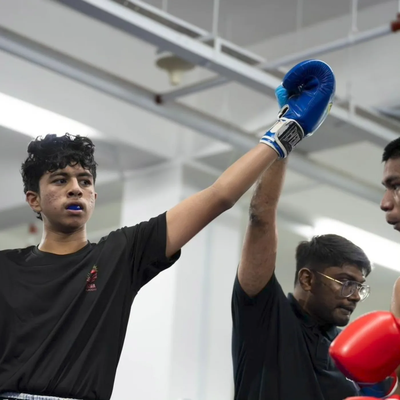 Referee raising the arm of a young AZMA athlete after a supervised amateur bout